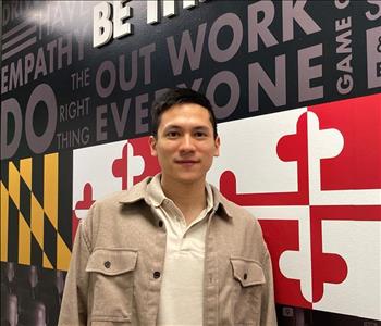 Hispanic male in beige shirt with Maryland flag in background